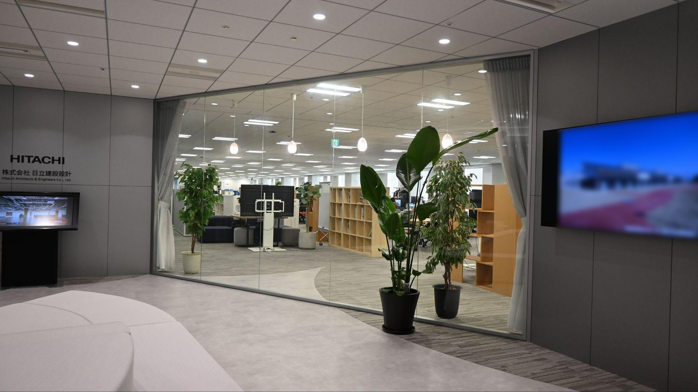 曲線的な床のパターンで待ち合いスペースと打ち合わせスペースをゾーニングしたエントランス